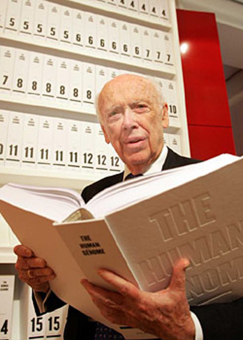 James Watson, one of the discoverers of the DNA double helix structure, reading the human genome in the Wellcome Wing of the Science Museum in London, UK. The 3.4 billion characters of the human genome are printed as a series of books, totalling over a hundred volumes, each a thousand pages long, in type so small that it is barely legible.